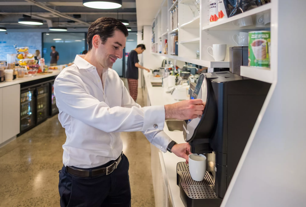 IMC Graduate Nevhan Ramadan Man making coffee in a coffee machine.