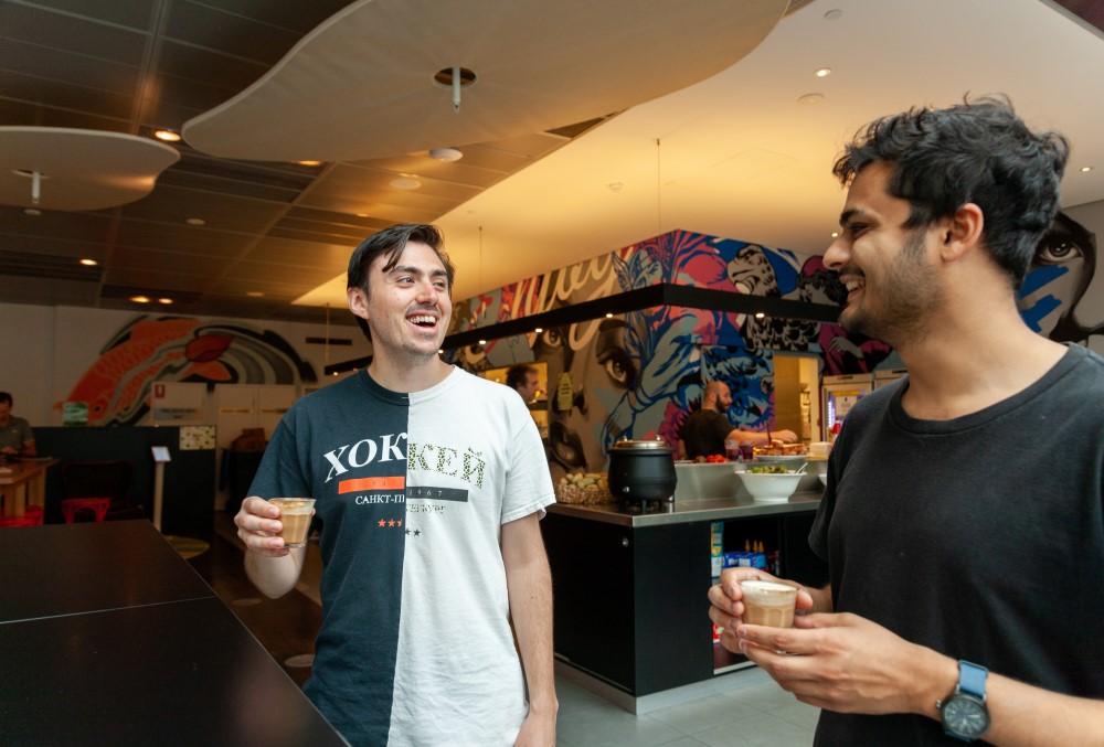 Optiver Graduate- A young male professional having coffee with his colleague.