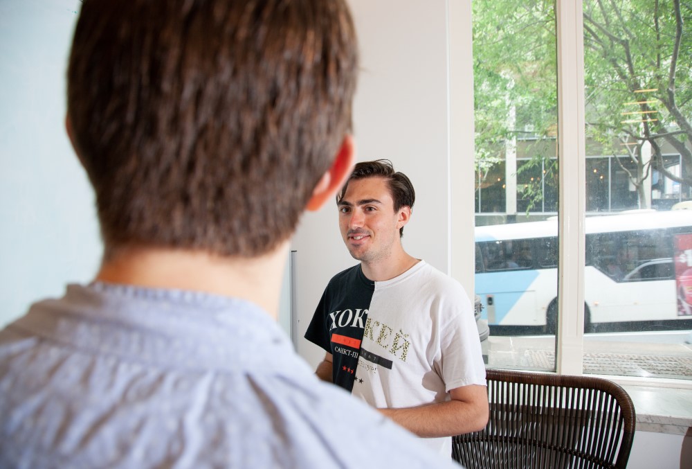 Optiver Graduate- A young male professional talking with his colleague.