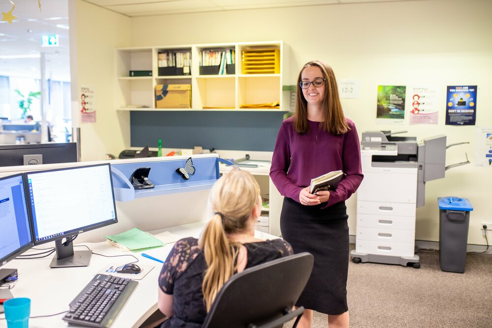Two young professionals talking inside the office
