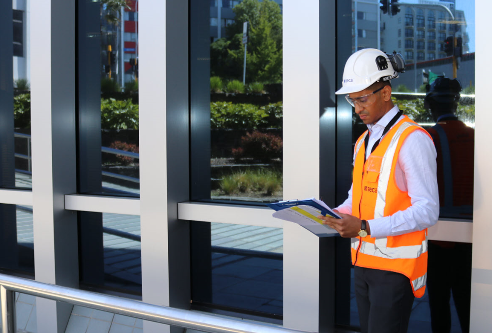 Beca Graduate- An engineer reviewing files while on site.