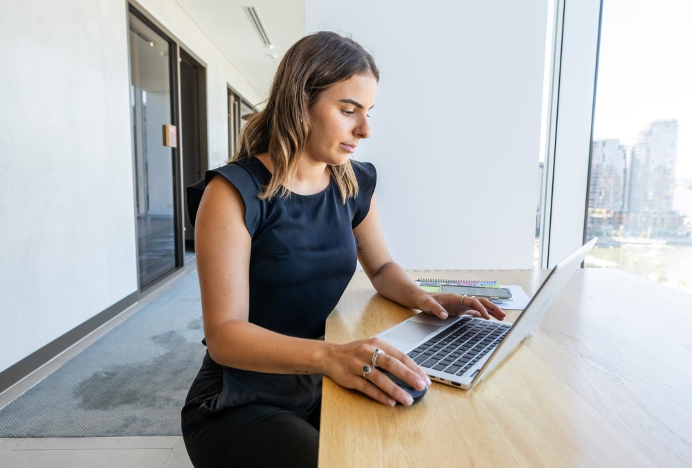 Deloitte Graduate- Young female professional checking her emails on her laptop.