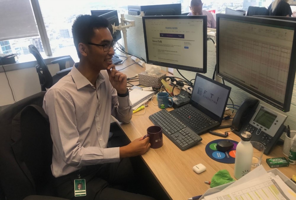 FTI Consulting Graduate - Young male professional sitting on his desk.