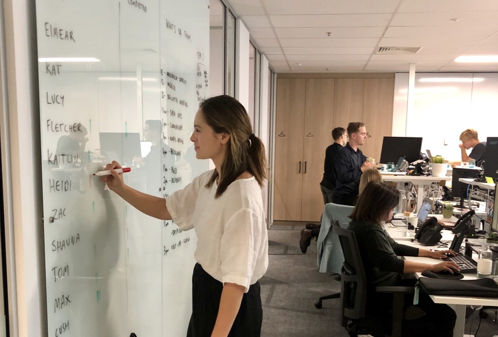 Meltwater Graduate - Young female professional writing on the board.